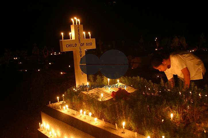 An Indian girl puts candle on a grave on the occasion of All Soul day in Kolkata