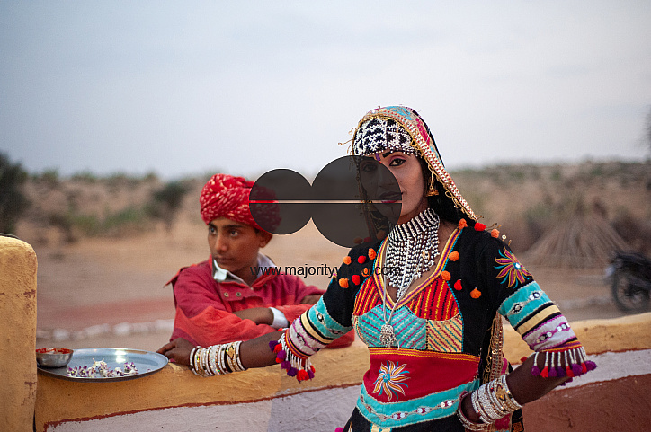  A musician and a dancer who perform for tourists in the desert wait outside the premises at dusk.