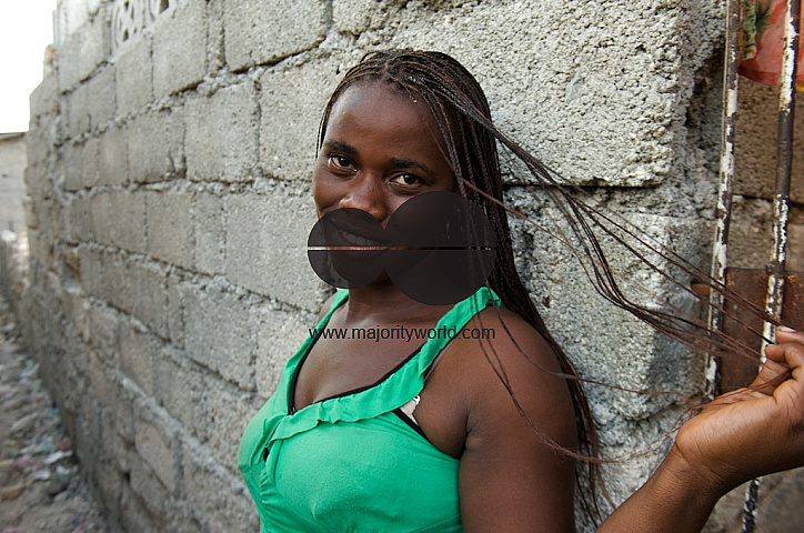 Haiti woman casually standing against wall smiling.