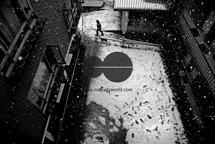 A worker in a hotel in Srinagar walks across the courtyard as it snows.