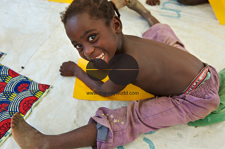  Sitting on the floor, a young Ivorian girl child