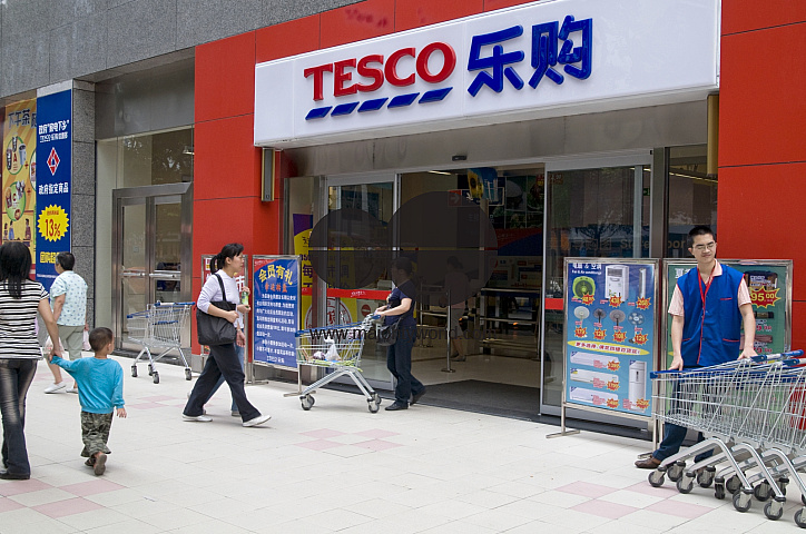 CHINA Shoppers walking past a Tesco store in Guangzhou, Guangdong province.