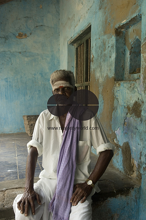 India. Man seated at entrance to his house.
