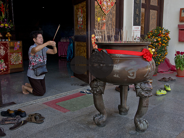 Elderly woman paying respect at a temple on the eve of Chinese New Year in Singapore
