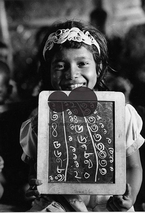 A girl child holds a slate with Bengla numerals