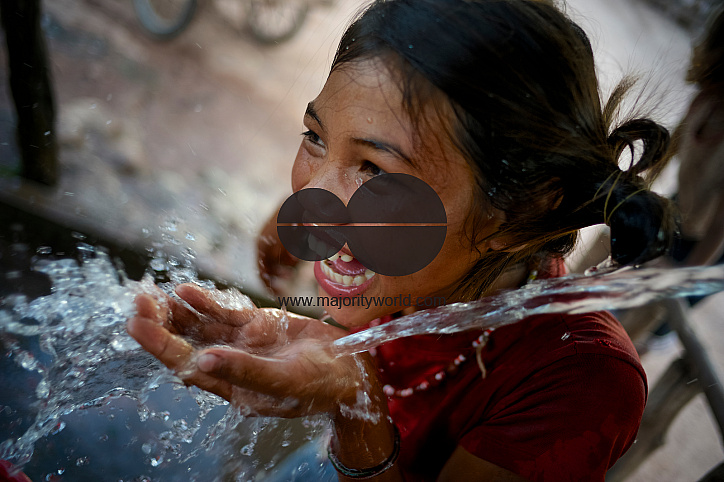  A girl laughs playfully laughs while drinking water