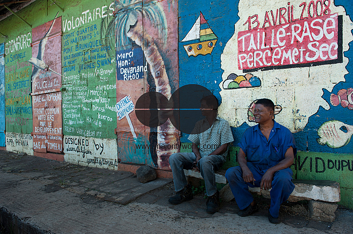 Mauritius. Men outside old building with graffiti.