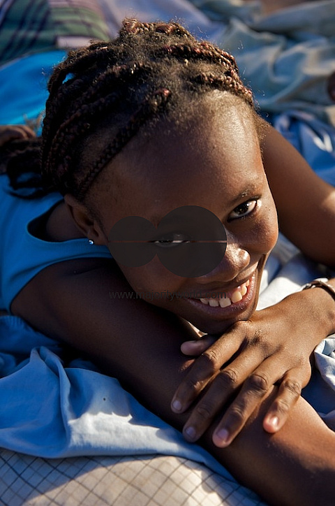 Young Haiti woman lying down smiling at camera.