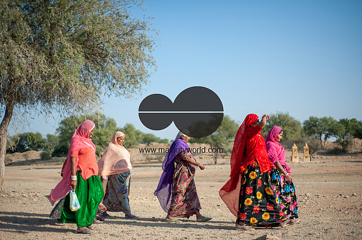 Women walk across an arid field on the outskirts of Jaisalmer.