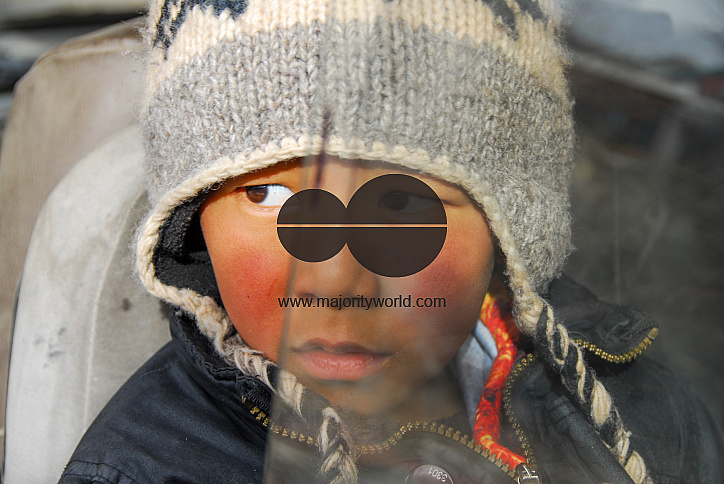 A boy looking out of the window of a stationary old Maruti Van parked in a backyard in Leh, Ladakh.