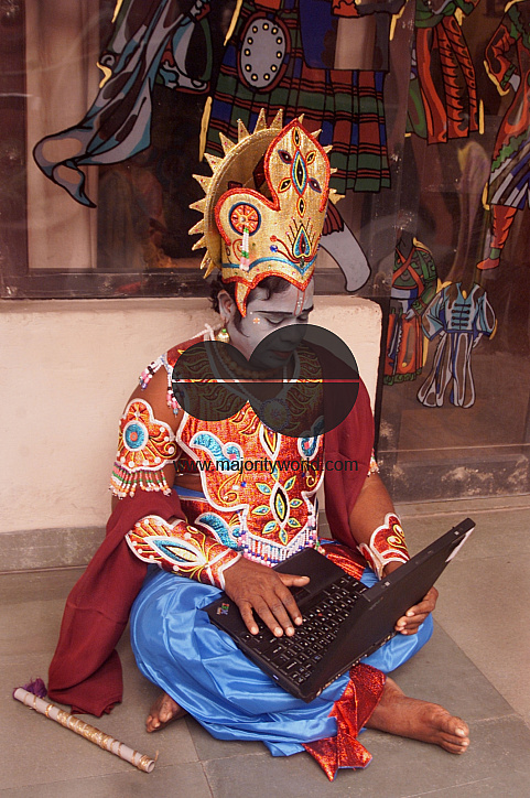 A South Indian dancer works with his laptop before a stage show at a dance festival in Kolkata