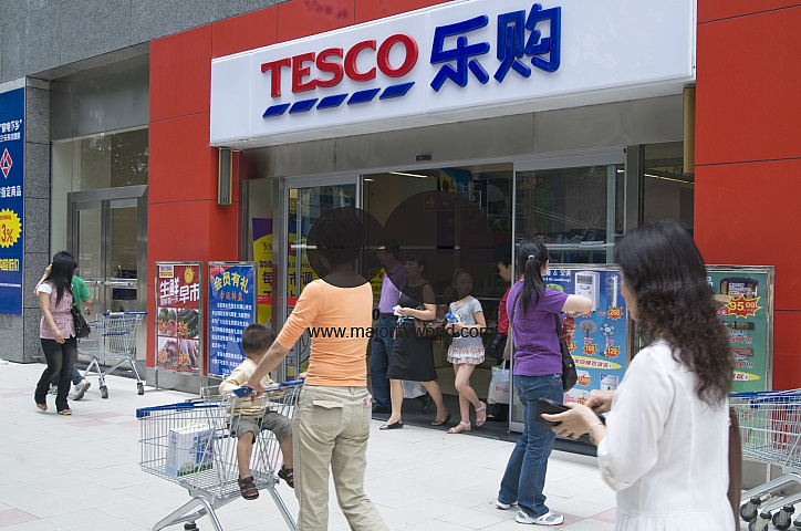 CHINA Shoppers walking past a Tesco store in Guangzhou, Guangdong province.