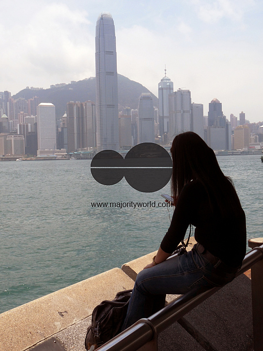 CHINA Woman checking her mobile phone with Hong Kong landscape in background.