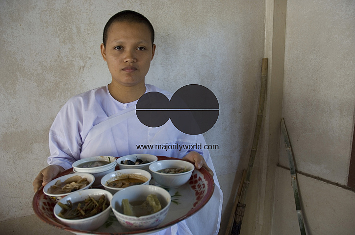 Thailand. Nun holding tray of food collected by monks.