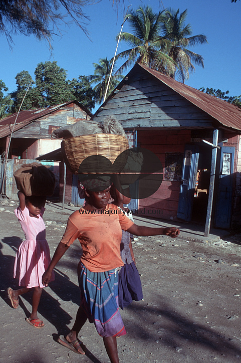 3 girls in a village carry items on head down local street