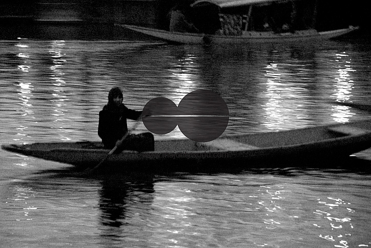 A Kashmiri boy rows across the Dal Lake at dusk.