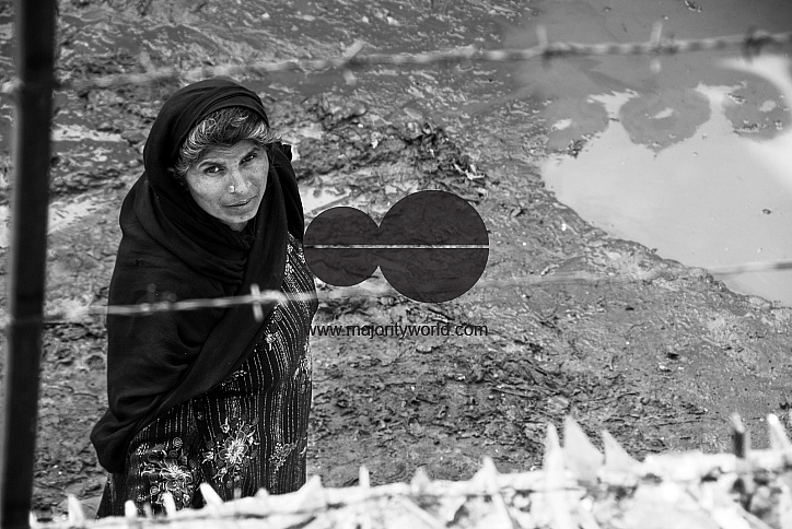  A woman looking though barbed wire and shards of glass, Lahore.
