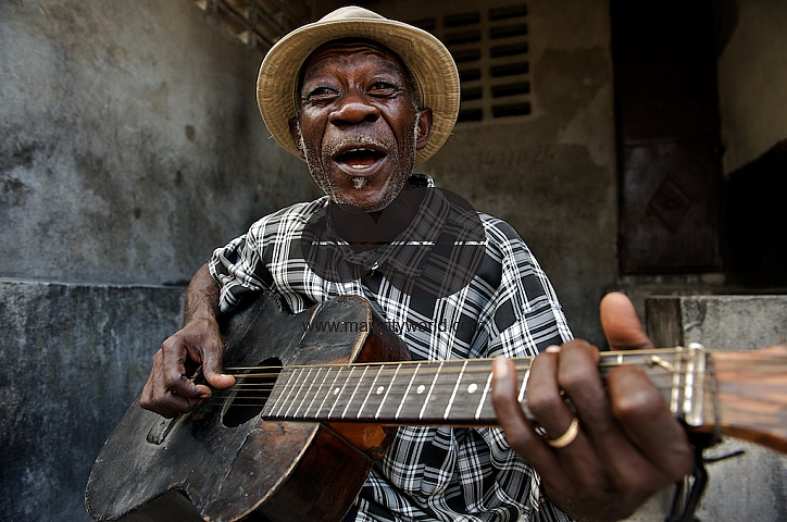 Haiti old man playing guitar on the street.