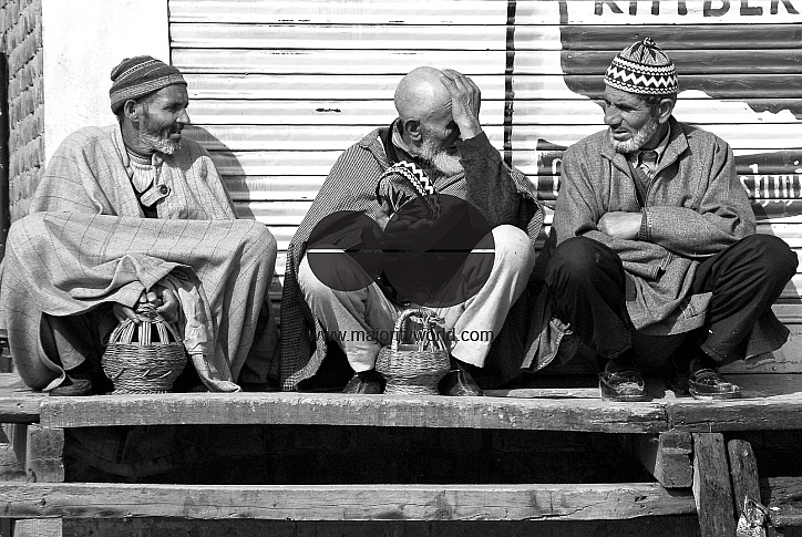 Three Kashmiri men talk by the side of the road.