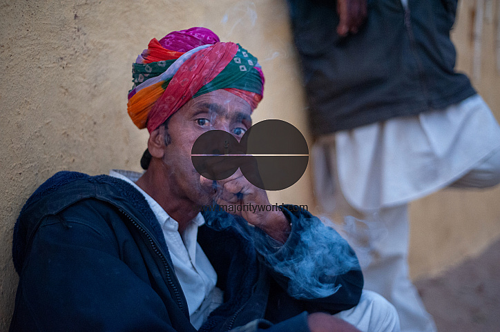  A musician who performs for tourists in the desert smokes a beedi as he waits.