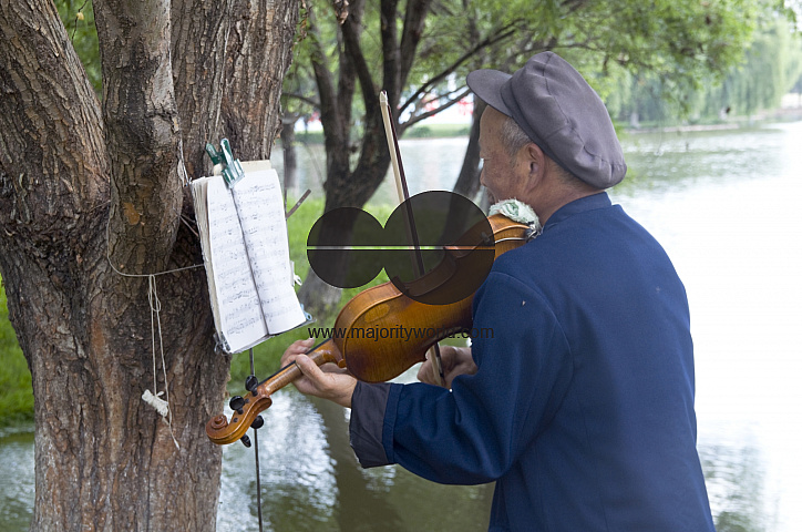 CHINA Elderly man playing the violin in a park in Kunming, Yunnan province..