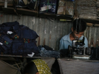 A young girl sewing by hand at a tailor shop. Bangladesh.