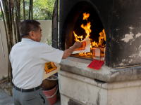 Elderly man burning paper money at a temple on the eve of Chinese New Year in Singapore