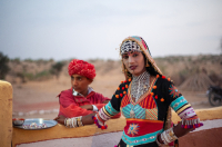  A musician and a dancer who perform for tourists in the desert wait outside the premises at dusk.