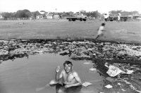NICARAGUA A REFUGEE FROM THE WAR ZONES HAVING A BATH IN A DIRTY POOL, DOWNTOWN MANAGUA,1990