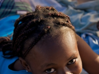 Young Haiti woman lying down smiling at camera.