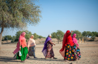  Women walk across an arid field on the outskirts of Jaisalmer.