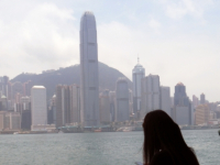 CHINA Woman checking her mobile phone with Hong Kong landscape in background.