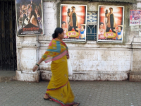 INDIA.People walking past an old picture house in Mumbai.