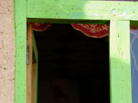  A girl child smiles standing at the window of her house