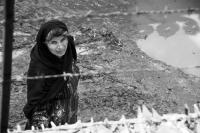  A woman looking though barbed wire and shards of glass, Lahore.