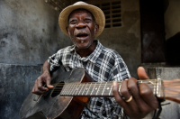 Haiti old man playing guitar on the street.