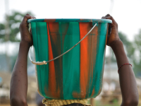  a young Ivorian girl child carrying a large bucket of water