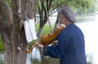 CHINA Elderly man playing the violin in a park in Kunming, Yunnan province..
