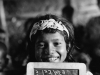 A girl child holds a slate with Bengla numerals